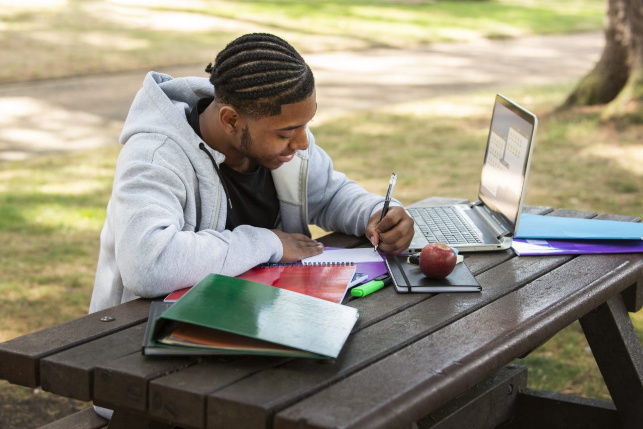 Nigerian student reviewing Chevening Scholarship eligibility requirements on a laptop, with the Nigerian and UK flags in the background.